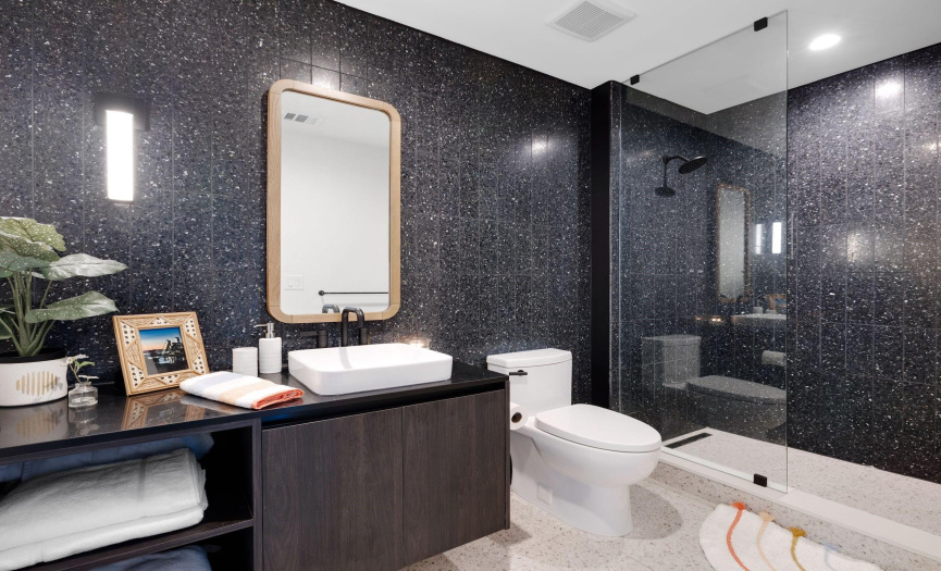The modern bathroom is absolutely stunning with tile walls and flooring along with an oversized single vanity and walk-in shower with frameless glass enclosure