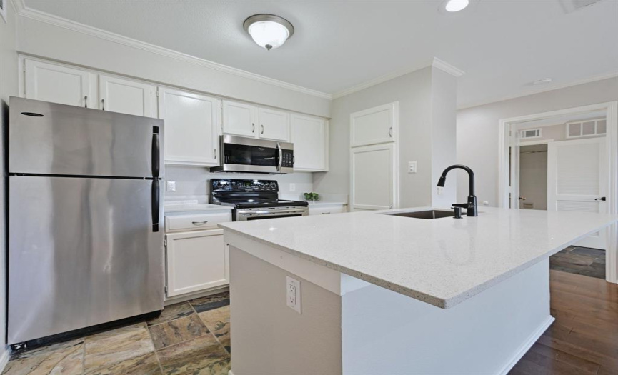 Adorned with quartz countertops and featuring a convenient breakfast bar with seating, the updated kitchen is as functional as it is stylish