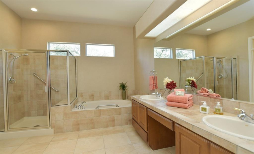Tile surrounds the shower and tub in this primary bath while transom windows add natural light.