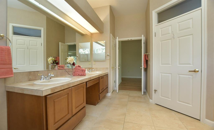 A seated vanity is found between two sinks in this primary bath as well as a private water closet.