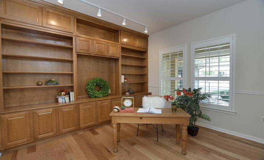 Off the foyer, floor-to-ceiling built-ins, plantation shutters and wood floors combine to create a handsome study/home office area.