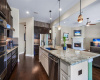 The expansive center island and breakfast bar beckon for friendly chats, while granite countertops, wood cabinetry, stainless appliances and a stylish tile backsplash fuse beauty and practicality