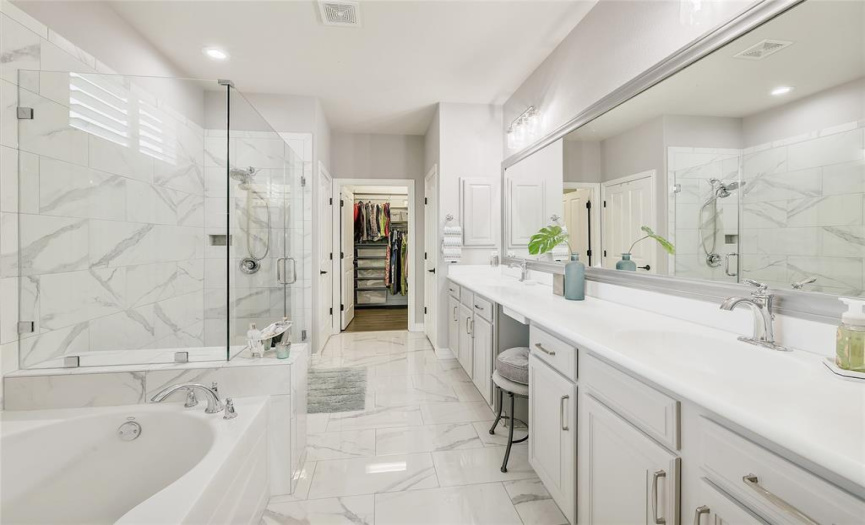 Ample elbow room and counter space on a lengthy dual sink vanity in the primary bathroom.