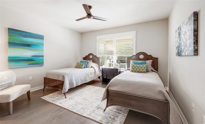 Bedroom 2 of 3 includes wood floors and greenbelt views via plantation shutters.