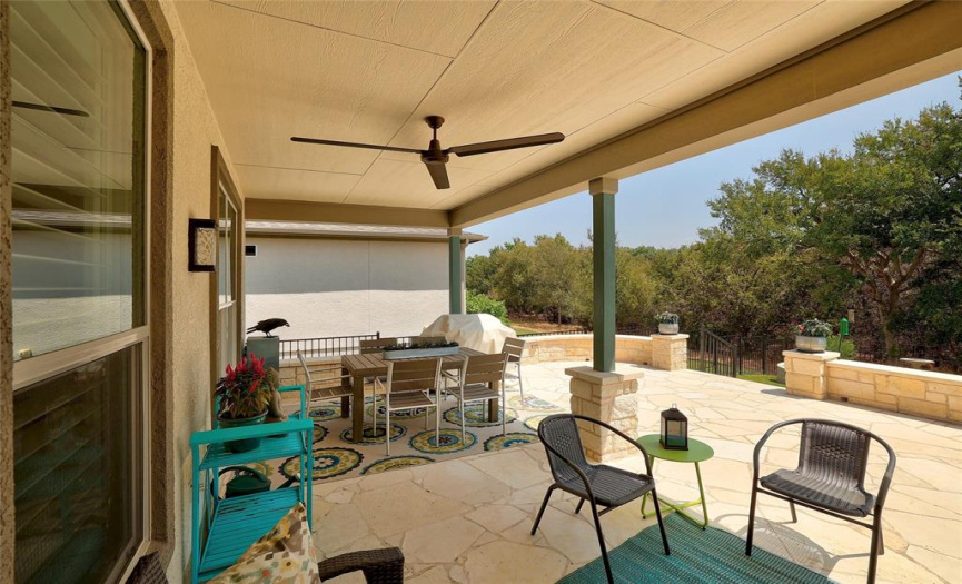 A covered and extended patio overlooks a deep greenbelt.