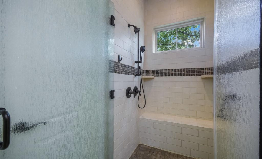 Enjoy a large built-in bench and Moen vertical shower set with separate handheld shower.