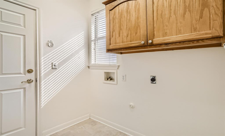 Laundry room has additional cabinets and window. 