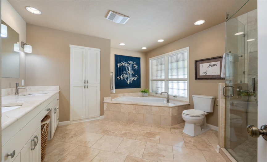 Updated Primary bathroom with heated towel rack, frameless shower, garden tub, and plenty of storage.