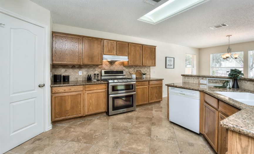 The kitchen features a gas range with double oven perfect for the holidays!  Granite counters, wood cabinets, and a double white sink...