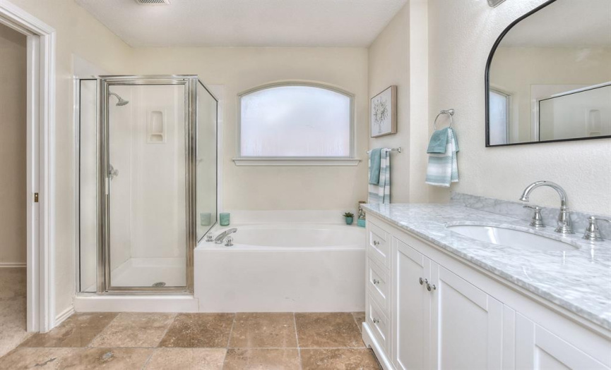 The primary bathroom provides pretty gray, large vanity with an arched mirror shaped the same as the arched window above the tub.  Get your bubble bath ready and let them take you away to a relaxing place.  Or take a warm shower if you prefer...