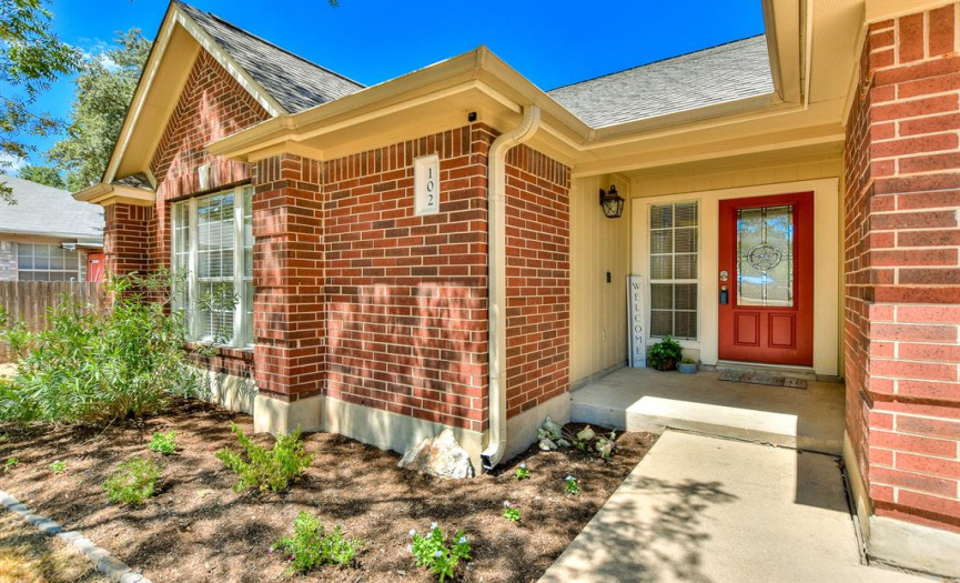 Beautiful red brick home with an inviting red front door!  Covered front porch, gutters, flower bed with mulch...