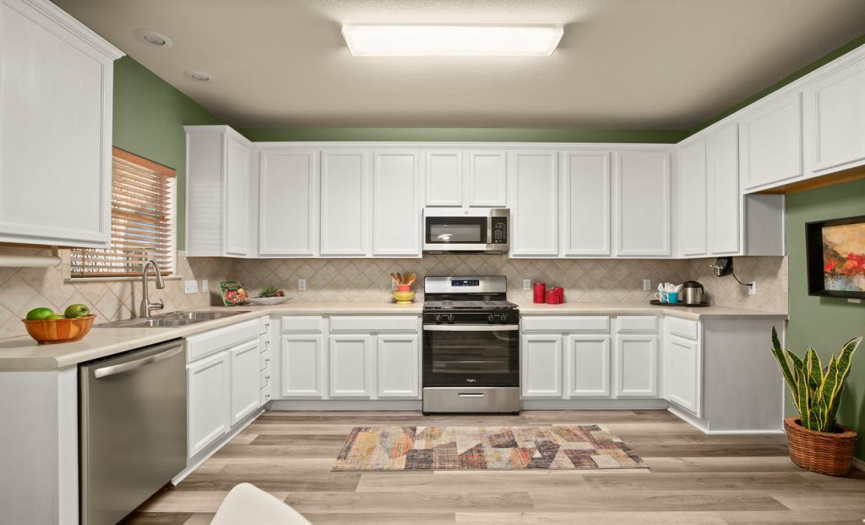 The spacious eat-in kitchen features easy to maintain wood-look vinyl flooring and plenty of space for adding a small center island. 