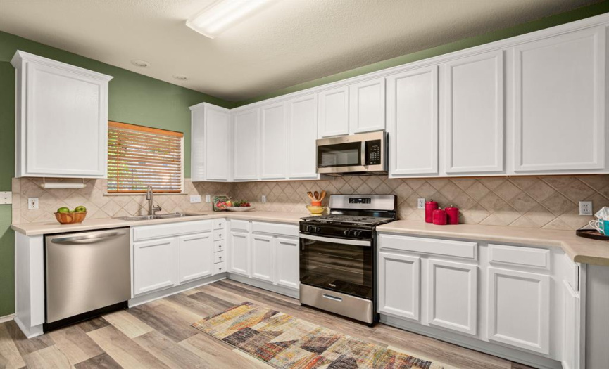 The bright & spacious kitchen features sleek stainless steel appliances including a gas range, microwave, and dishwasher. 