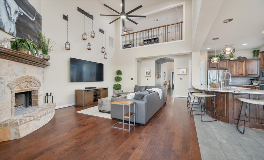 Main living space with oversized fan and approximately 20 foot tall ceilings with wood burning fireplace