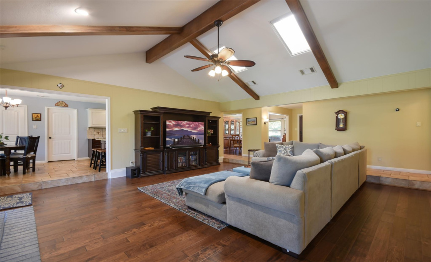Large great room with beamed ceilings, sky lights, gas fireplace and hardwood floors.