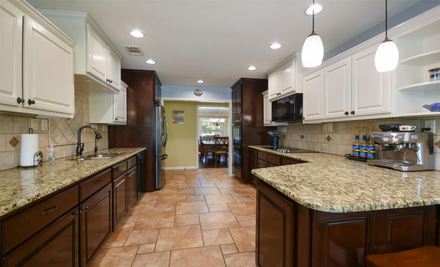 Enjoy this updated kitchen and white and dark cabinetry, granite, tile back splash, double oven, electric cooktop and microwave.