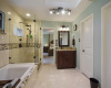 Beautifully appointed primary bathroom with marble floors, granite counters, knotty alder cabinets