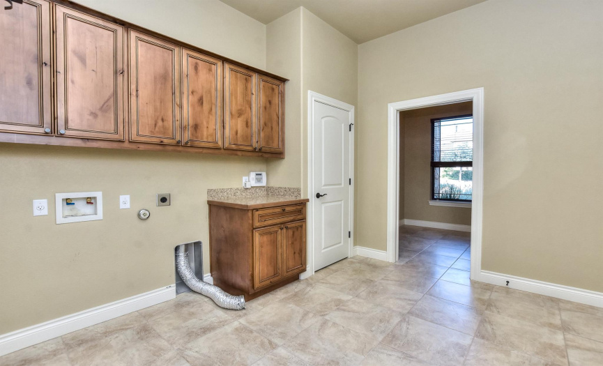 Oversized laundry room has extra cabinets for storage and a storage closet/or craft room.