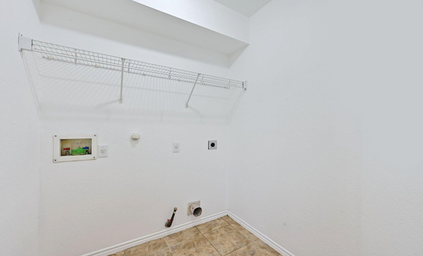 The laundry room has a shelf above the W/D connections for storage.