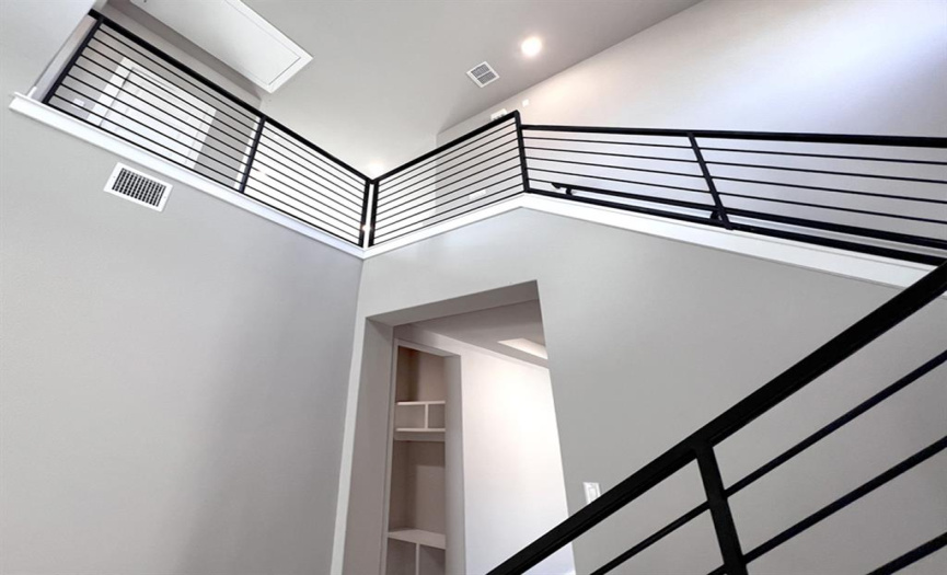 Modernized horizontal iron stair railing to upstairs - drop area/mud room in background