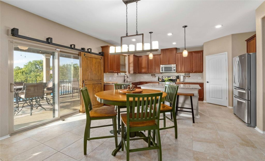 The bright and spacious eat-in kitchen also provides a sunny dining area with a chic chandelier fixture. Sliding doors lead to the covered back porch and feature stylish sliding barn doors in lieu of curtains. 