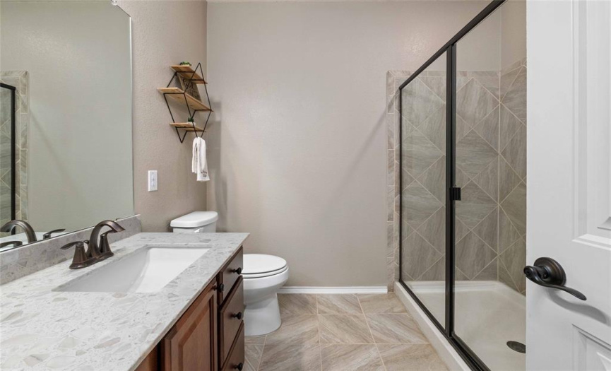 The spacious secondary bathroom is sure to impress with the lovely designer countertop, walk-in shower, and gorgeous tile work. 