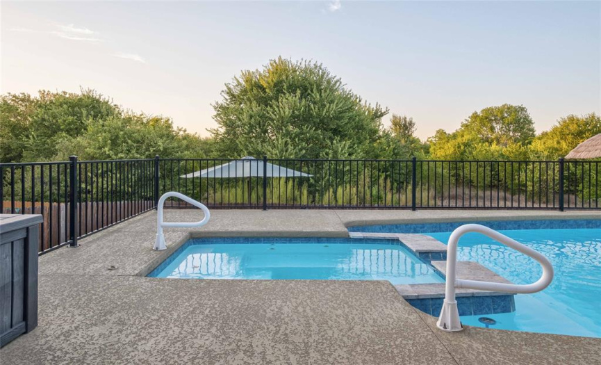 Imagine cooling off in the sparkling in-ground pool or warming up in the spa while gazing out onto the peaceful wooded area behind the home. 