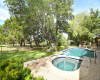 A fenced back yard and mature trees surround the pool at this beautiful home.