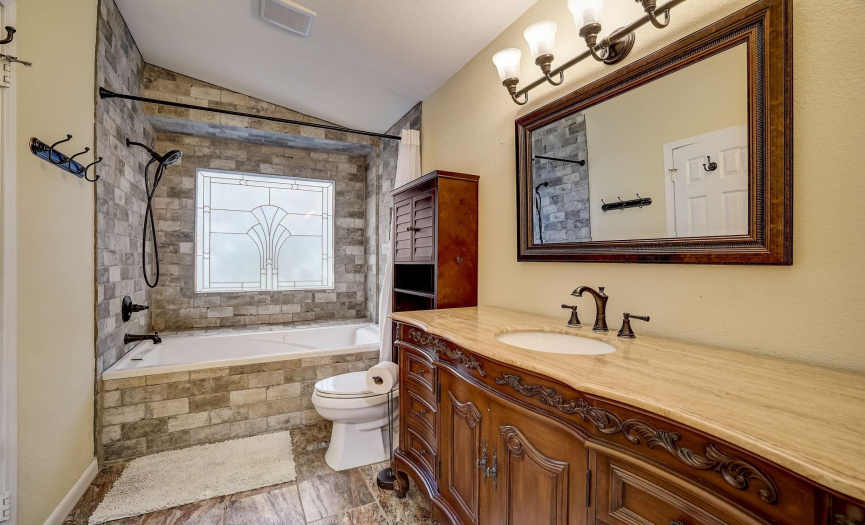 Primary Bathroom with custom stone work, oversized jacuzzi tub and walk in closet.