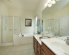 Separate vanities, garden tub and separate shower are found in the primary bath with generous natural light coming in from a picture window and an upper transom window as well.