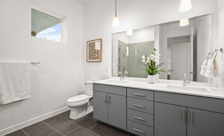 The primary en-suite bathroom offers modern amenities, including a quartz-topped dual vanity.