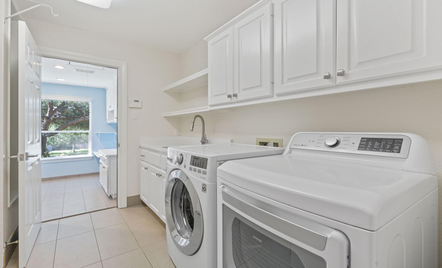 There is plenty of room in this nice laundry room with a sink, room for a second refrigerator, and 2 storage closets. The washer and dryer conveys with the home.