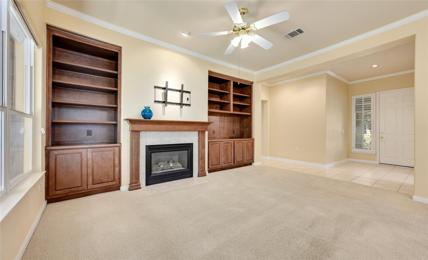 Gas log fireplace, 10' ceilings, crown molding and built-in cabinets in open living room.