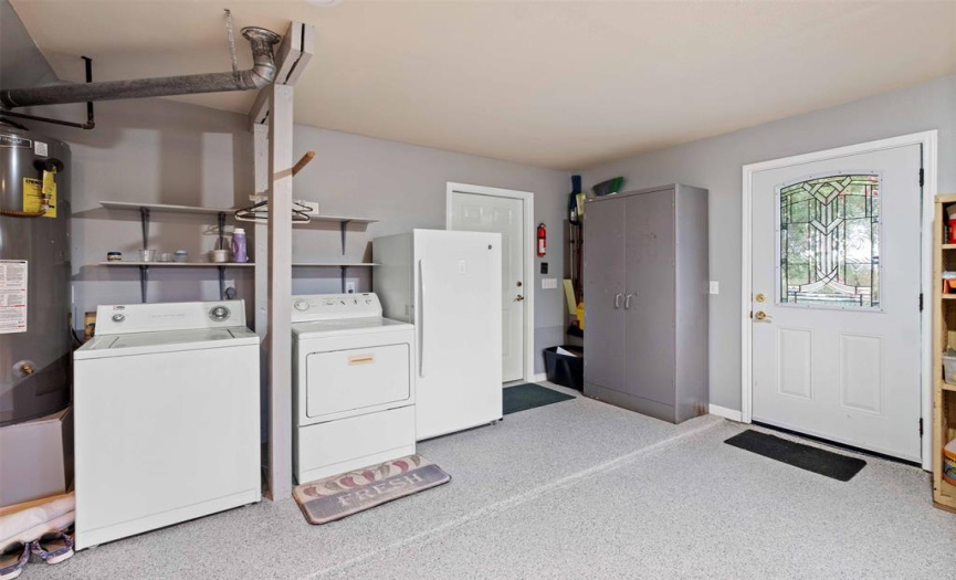 Two car garage with epoxy floor.  This is your laundry room!  Fridge shown does not convey, all other shelving conveys.  The one light door exits to the walk way to the outdoor covered porch and the above ground pool!