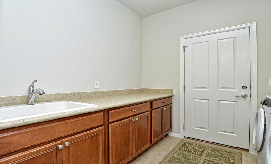 Laundry room with useful wash basin opens from home into garage with a no-steps, kitchen level garage floor.