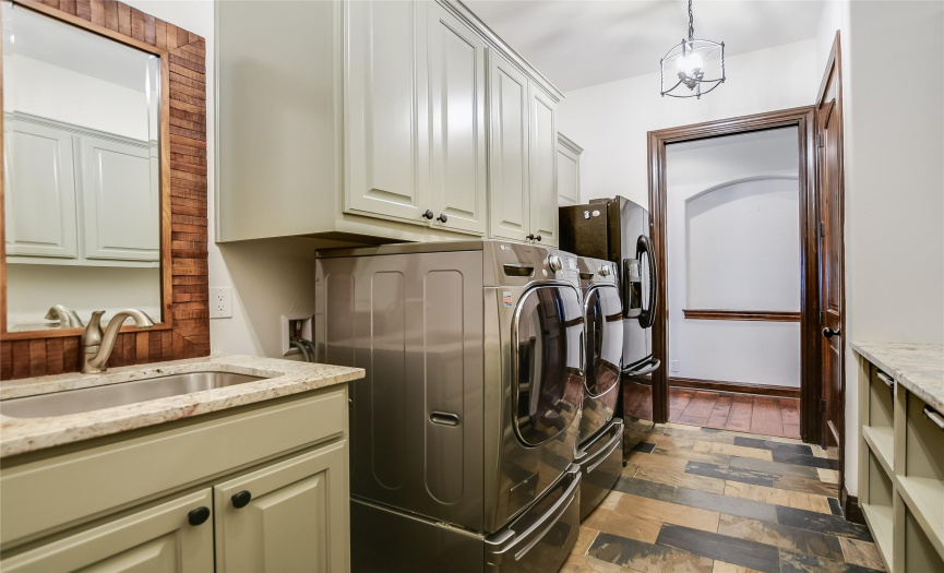 The laundry room has storage galore, a stainless steel sink and granite countertops.