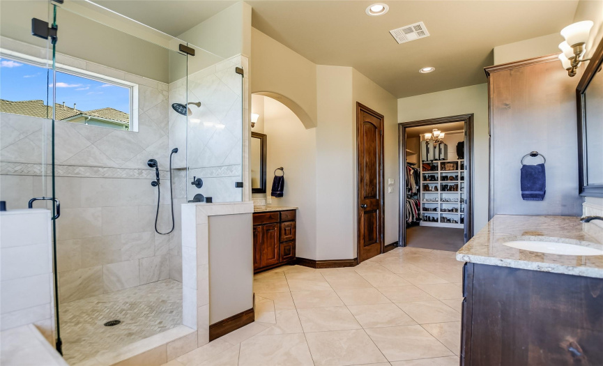 The spa-inspired primary bathroom features dual vanities, a step-in shower with a frameless glass enclosure and a massive walk-in closet.