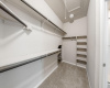 Walk in primary closet with extra under stairs storage 