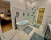 View of the lovely freestanding tub and separate shower with frameless glass surround. Large closet in the background.