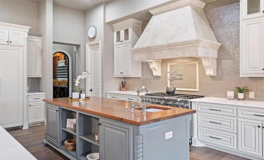 The polished butcher's block center island with built-in prep sink and hidden trash can provides generous countertop space for preparing meals. 