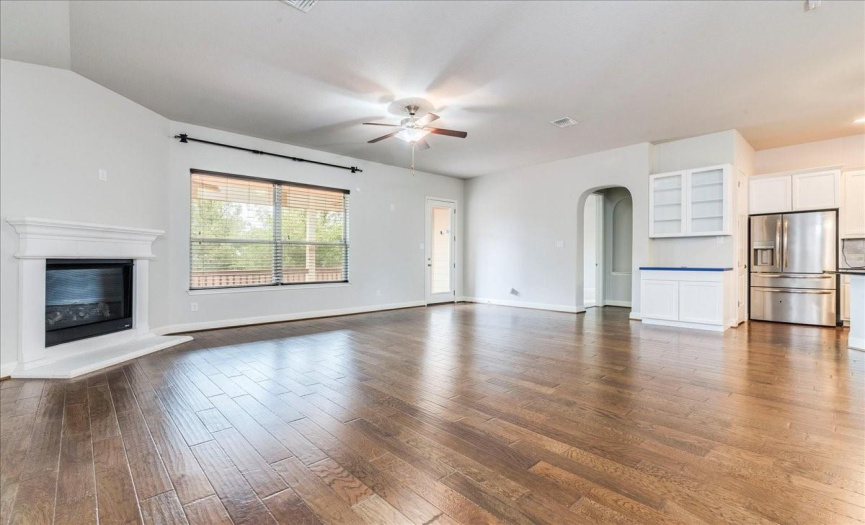 Spacious Open Family Room With Beautiful Wood Floors, Cozy Corner Fireplace & Wall Of Windows