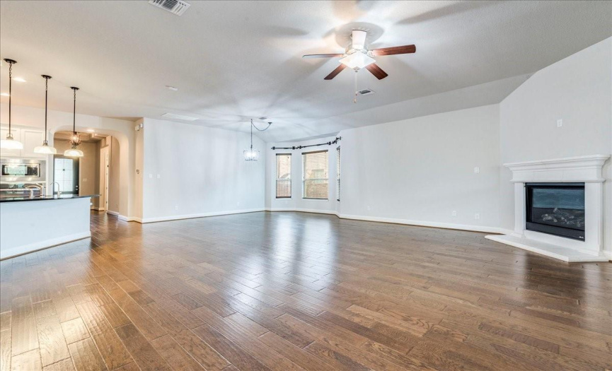 Spacious Open Family Room With Beautiful Wood Floors, Cozy Corner Fireplace & Wall Of Windows