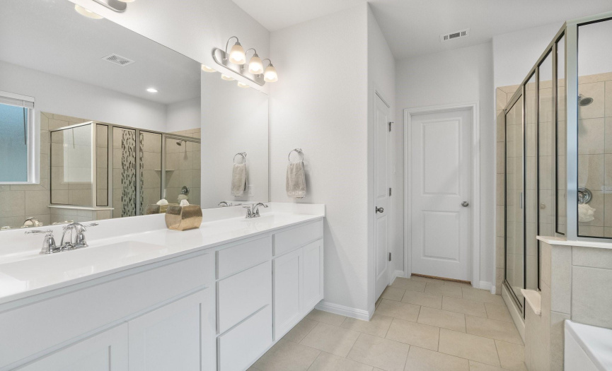 The primary bathroom boasts a dual vanity, deep soaking tub, and separate walk-in shower for your daily pampering.