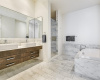 Luxurious bathroom with marble tile and Duravit tub and dual vanities.