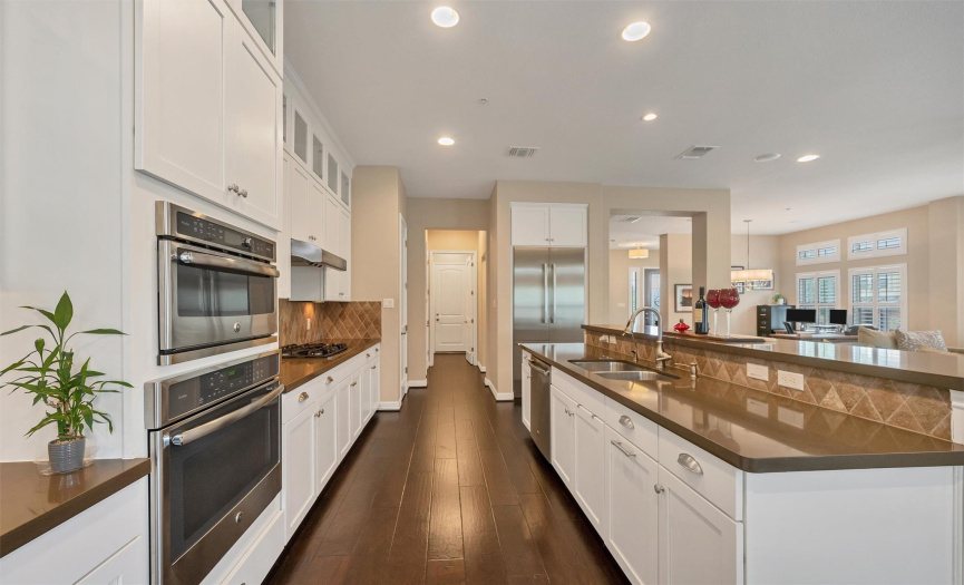 Glittering quartz counters, stainless steel appliances, a built-in microwave & oven, a built-in fridge, & a gas cooktop.