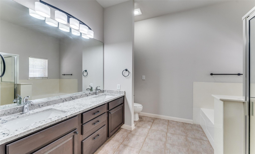 View of Primary Bathroom with double vanities featuring new granite, new lighting, fixtures, and hardware.  Linen closet, separate shower and jetted tub.