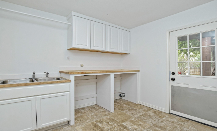 Large, indoor laundry with sink and access to backyard.