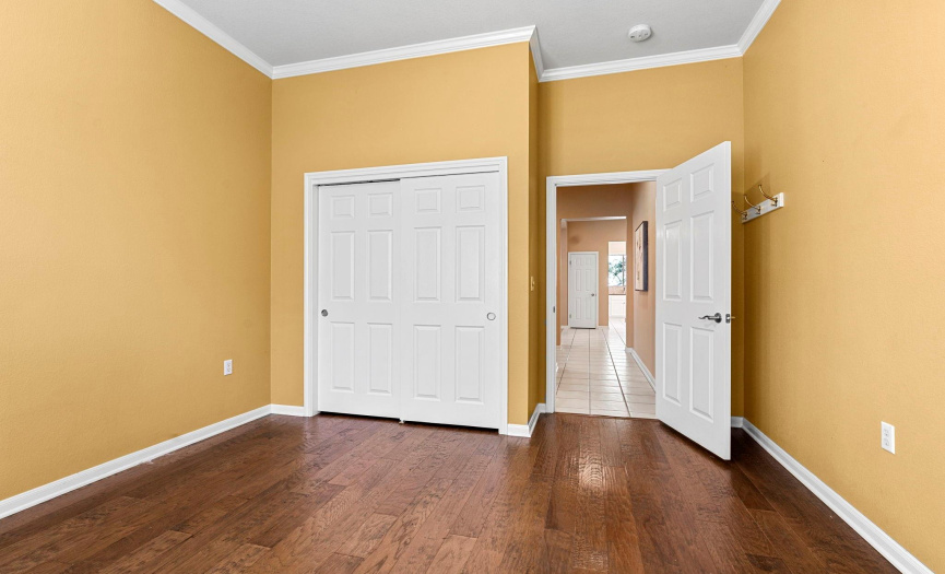 The secondary bedroom has tall ceilings, crown molding and hardwood floors.