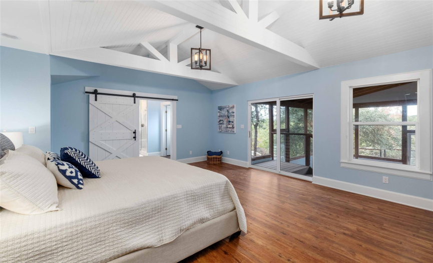 Main level primary bedroom features an en suite bathroom, dual vanities, a walk in closet, (a hidden door bookcase!) and access to the inviting screened in porch
