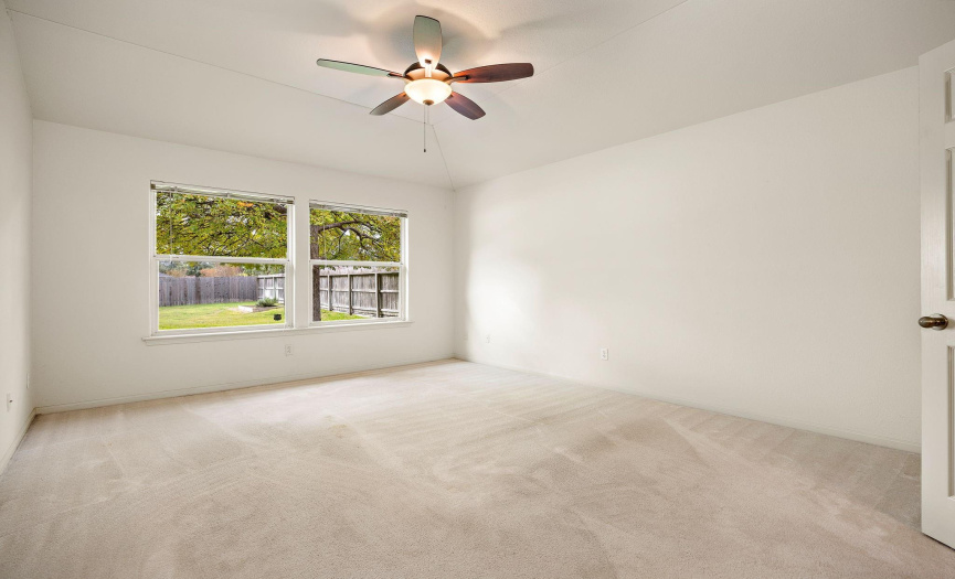 Primary Bedroom- What a great space to relax and retreat! It offers a ceiling fan and windows that overlook the beautiful backyard. 